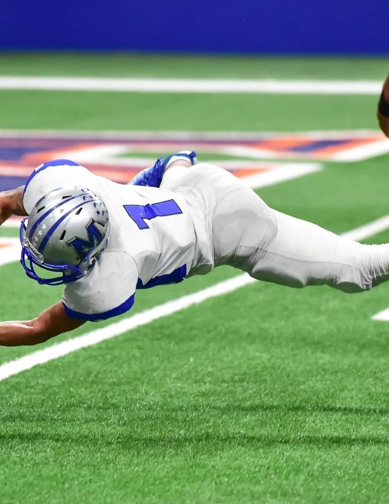 Football player diving for the ball at High Point Chiropractic athletics event in Superior, Colorado